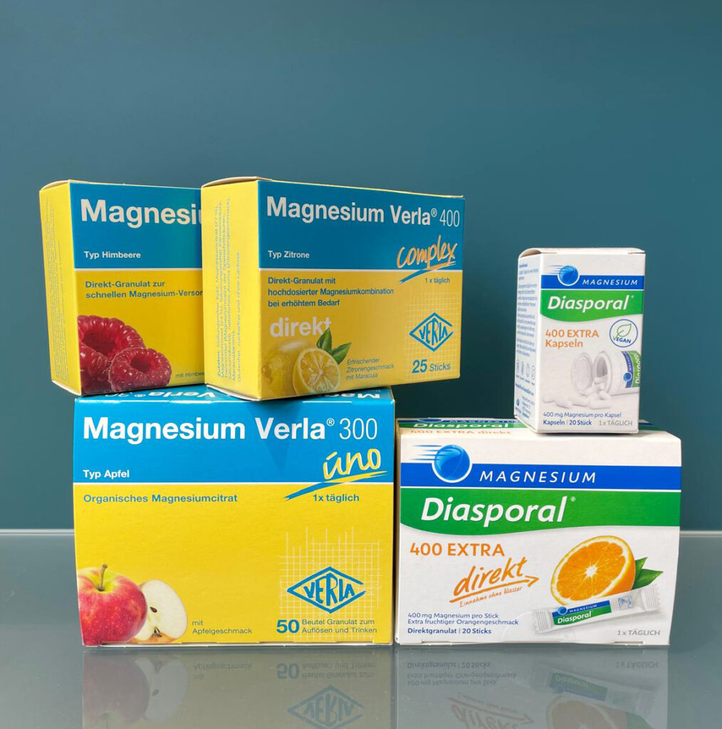 Produktfoto von fünf verschiedenen Magnesium-Präparaten der Marken Verla und Diasporal mit Fruchtmotiven vor blauem Hintergrund