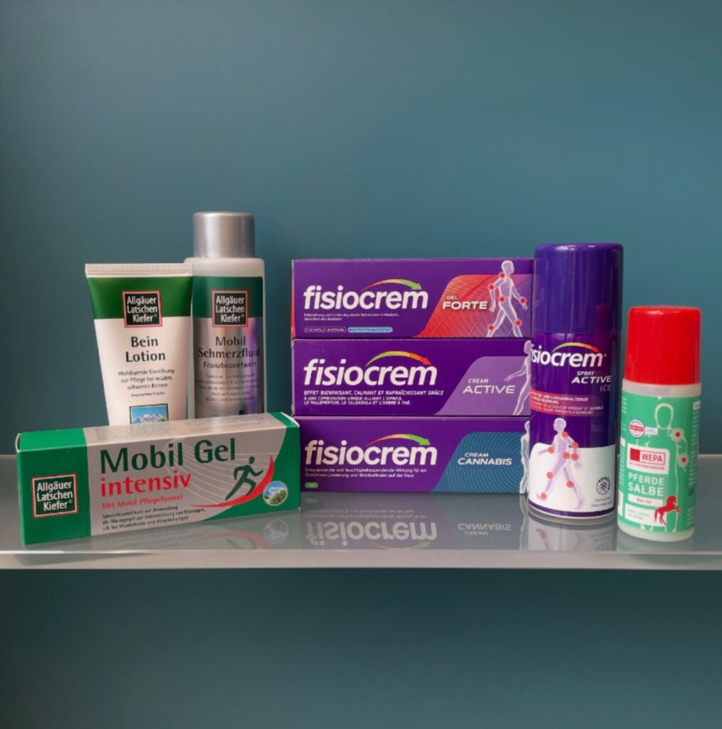 Drei übereinandergestapelte, violette Schachteln der Marke „fisiocrem“ mit den Produktnamen „Gel FORTE“, „CREAM ACTIVE“ und „CREAM CANNABIS“.
